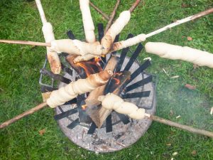 baking camp bread on sticks over an open fire